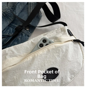 Close-up of white pleated nylon shoulder bag with front zipper pocket for smartphone storage