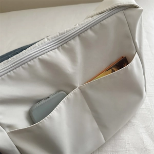 White minimalist nylon tote bag with functional dual front pockets and top zipper closure