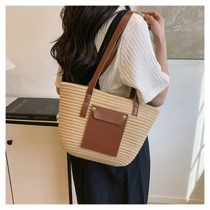 Model showing large beige woven tote bag with brown leather straps in a minimal setting