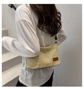 Detail of hand-woven beige straw bag with premium brown leather strap on model