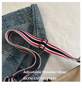 Détail de la bandoulière tissée réglable à rayures rouges, blanches et bleues sur un sac kaki