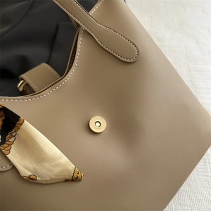 Khaki leather tote bag with white contrast stitching and printed silk scarf handle