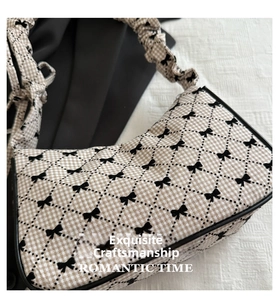 Detail of checkered shoulder bag with black bow prints and ruched handle strap
