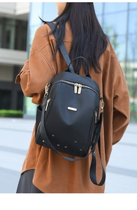 Vue arrière extérieure d'une femme portant le sac à dos noir en nylon à plusieurs zips