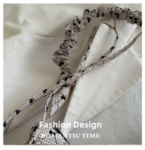 Detail of checkered fabric hair scrunchie with black floral patterns on soft background