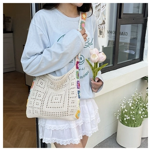 Detail of hollow woven beige shoulder bag with colorful floral crochet strap design