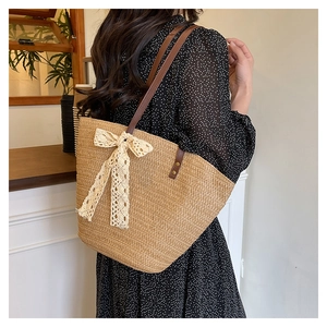 Detail of hand-woven straw tote with elegant lace bow and brown leather strap