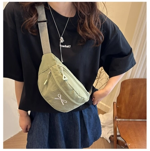 Détail d'un sac bandoulière vert clair avec motif nœud blanc et doubles fermetures