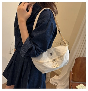 Detail of white nylon crossbody bag with dual zippers and adjustable fabric strap