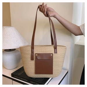 Detail of a beige woven tote bag with brown leather pocket and rivet accents