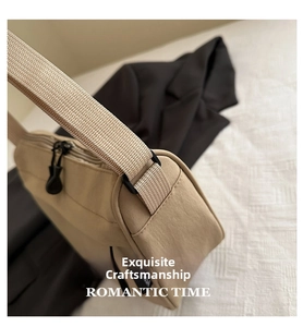 Detail of a beige water-resistant tote bag with wide strap and black zipper hardware