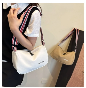 Close-up of canvas crossbody bag featuring red, white, and blue striped wide strap
