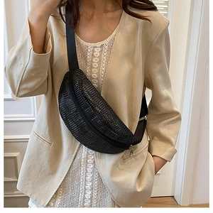 Détail d'un sac de poitrine noir à strass porté sur une veste de costume beige