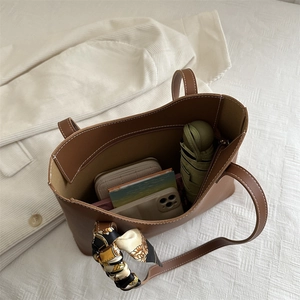 Brown leather tote bag with contrast stitching, scarf detail, and spacious interior view