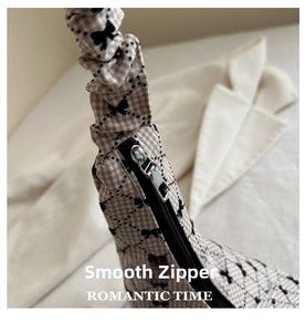 Macro view of smooth silver zipper and plaid fabric with bow print on shoulder bag
