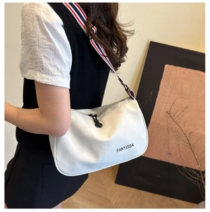 Détail du sac blanc FANYISSA avec bandoulière à rayures rouges, bleues et blanches