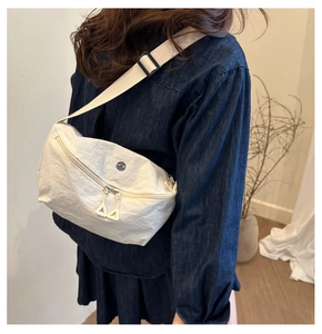 Rear view of a model wearing a cream nylon half-moon crossbody bag with wide strap