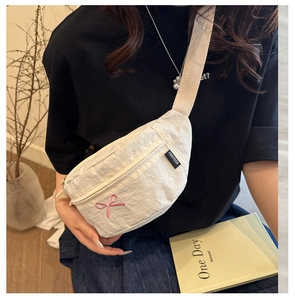 Close-up of white crossbody bag featuring pink bow embroidery and FANYISSA label