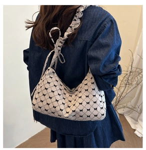 Detail of vintage plaid shoulder bag featuring a black bow and ruffled strap on a model