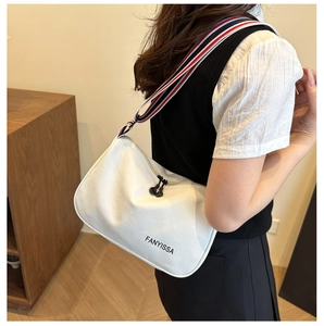 Detail of white crossbody bag with striped strap and black FANYISSA brand lettering