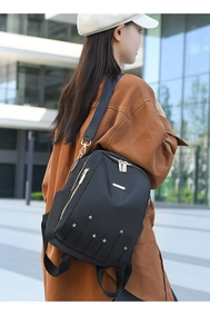 Détail du sac à dos en nylon noir avec des clous en étoile dorés et fermetures métalliques