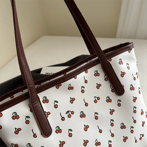 Large tote bag with red cherry print and dark brown leather handles for daily commute