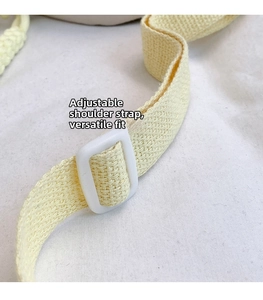 Detail of adjustable pale yellow woven shoulder strap with white plastic buckle