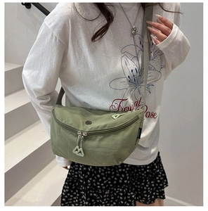 Détail du sac selle en nylon vert léger avec double fermeture éclair et logo de la marque