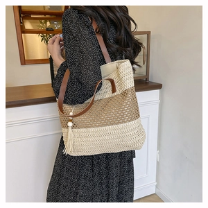 Detail of woven straw tote bag with horizontal stripes, brown leather strap and wood bead tassel