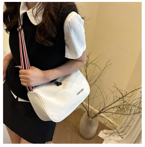 Détail du sac bandoulière blanc avec sangle tricolore et marquage du logo FANYISSA