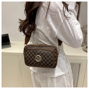 Detail of vintage monogram crossbody bag with gold M logo and wide strap on model