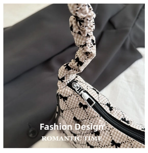 Detailed close-up of checkered fabric handbag with bow print and ruffled handle