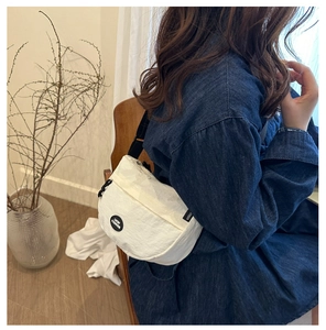Detail view of white nylon crossbody bag featuring the black Lucky Fashion logo patch
