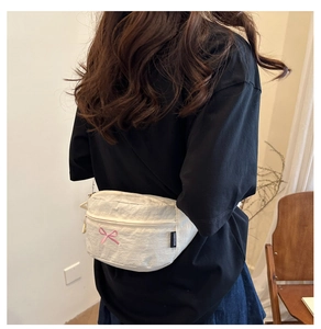 Gros plan sur un sac blanc avec broderie de nœud rose et texture de tissu froissé