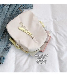 Detail of cream nylon crossbody bag showing spacious interior with phone and notebook
