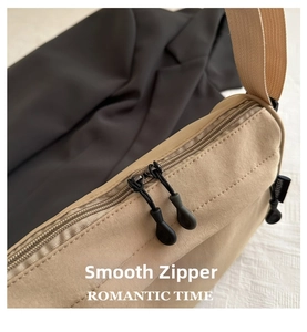 Detailed close-up of durable dual zippers and nylon fabric on beige shoulder bag
