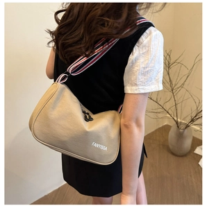 Detailed back view of a beige canvas crossbody bag with colorful woven shoulder strap