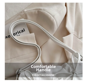 Detail of elegant cream bow tote bag showing fine leather straps and neat stitching texture