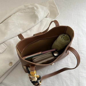 Brown large capacity leather tote bag with white stitching and floral silk scarf accessory