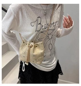 Detail of straw woven bucket bag with pink flower embroidery and gold chain strap