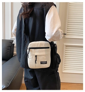 Close-up of cream canvas crossbody bag featuring functional pockets and fashion instinct logo