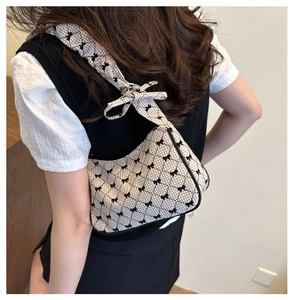 Detail of checkered shoulder bag featuring bow patterns and 3D bow on the strap