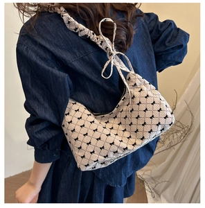 Detail view of beige canvas shoulder bag featuring black bow prints and ruffled strap