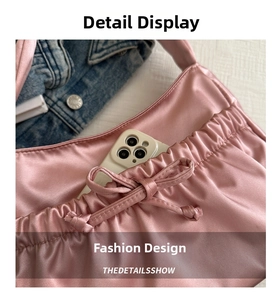Détail d'un sac à main plissé en satin rose avec nœud et espace pour un smartphone