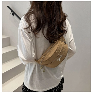 Detail of khaki nylon sling bag with white bow embroidery and triangle zipper pull