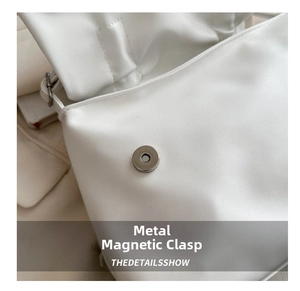 Detail of silver magnetic closure on a white leather shoulder bag with sleek finish