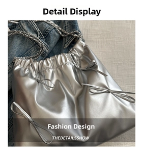 Detail of silver metallic drawstring bucket bag with bow accents and chain strap