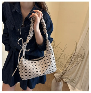 Detailed view of canvas shoulder bag featuring plaid patterns and bow tie details on strap