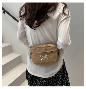 Détail du sac demi-lune en nylon kaki avec broderie nœud blanc et fermeture éclair en métal
