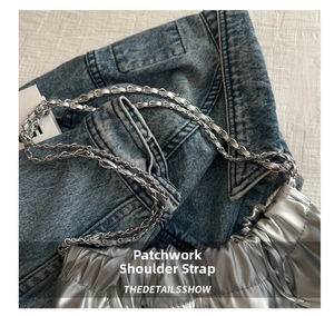 Detailed view of silver metallic shoulder bag with mixed chain and leather strap on denim